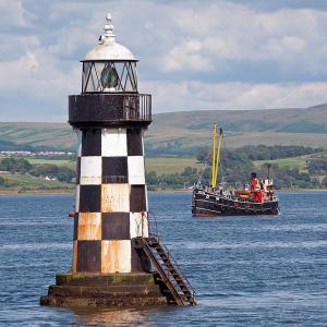 a boat in a body of water next to a lighthouse at Blackthorn Manor in Greenock