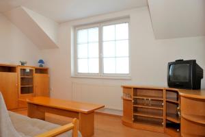 a living room with a table and a tv at Penzion Šenk Pardubice in Pardubice