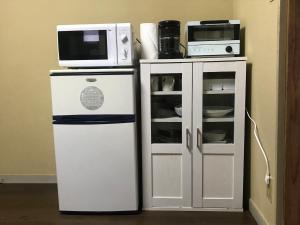 a microwave on top of a refrigerator next to a cabinet at YabFarm Lodge 102 in Kashiwa