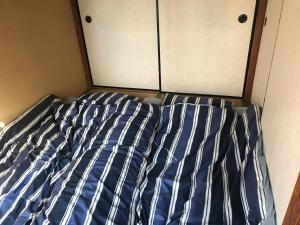 a bed with a blue and white striped comforter at YabFarm Lodge 102 in Kashiwa