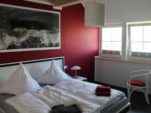 una camera con un letto bianco con una parete rossa di Holiday apartment with 2 bedrooms a Hof Dranske