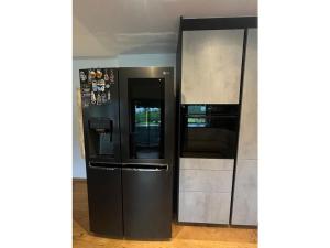 Un gran refrigerador negro al lado de una pared. en Holiday apartment Robin, en Waidring