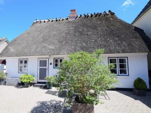 una casa blanca con techo de paja con pájaros en el techo en Holiday home in Maasholm with swimming pool, en Maasholm 17 fotos más