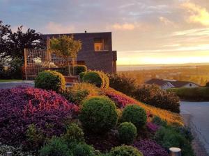 ein Haus auf einem Hügel mit einem Blumengarten in der Unterkunft holiday apartment in Backenreute