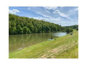 eine Gruppe von Menschen, die auf einem Feld neben einem See stehen in der Unterkunft Holiday home Talblick 13 in Burgwallbach