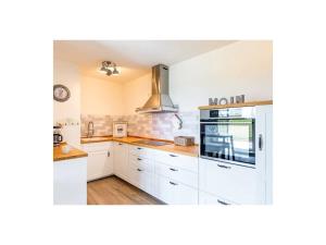 a kitchen with white cabinets and a stove top oven at Dream holiday under a thatched roof in Brunsbüttel