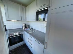 eine kleine Küche mit weißen Schränken und einer Spüle in der Unterkunft Holiday apartment with 1 bedroom in Maasholm + 23 Fotos