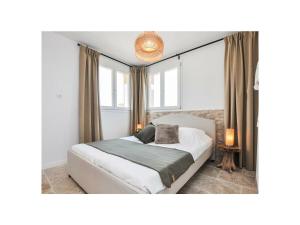 een slaapkamer met een bed en twee ramen bij Maison Laurier Rose in Plan-de-la-Tour