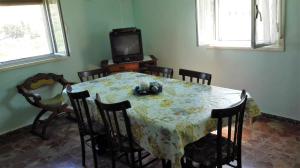 una sala da pranzo con tavolo, sedie e TV di Casa Vacanze S.Andrea a Lascari