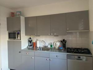 a kitchen with white cabinets and a sink and a refrigerator at Holiday home in Makkum with swimming pool in Holle Poarte