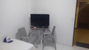 um quarto com uma secretária com um monitor de computador e cadeiras em Estúdio Ibiza II em Maceió