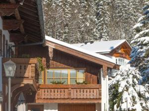 een houten huis met een balkon in de sneeuw bij House Alpenlicht in Reit im Winkl