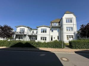 una grande casa bianca seduta sul lato di una strada di Villa Marin, Apartment 6 a Zinnowitz
