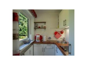 Holiday apartment with 1 bedroom في Kirchberg: مطبخ بخزائن بيضاء ومغسلة ونافذة