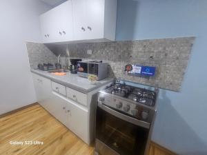a kitchen with a stove and a microwave at Hospedaje Familiar Ecuador in Cuenca