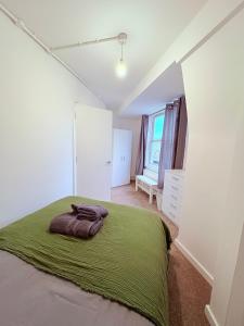 Un dormitorio con una cama con una manta verde encima. en BRAND NEW 3 bed flat for 6 people near of Chelsea Stadium with welcome breakfast, en Londres