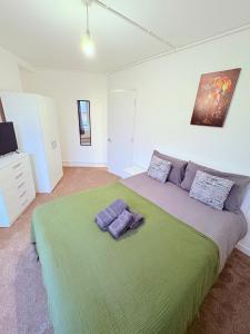 Un dormitorio con una cama grande con una manta verde. en BRAND NEW 3 bed flat for 6 people near of Chelsea Stadium with welcome breakfast, en Londres