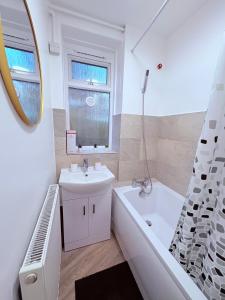 Baño blanco con lavabo, bañera y espejo en BRAND NEW 3 bed flat for 6 people near of Chelsea Stadium with welcome breakfast, en Londres 136 fotos más