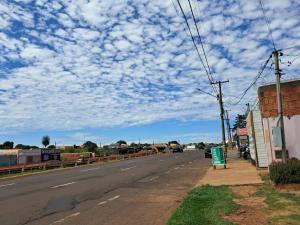 an empty street with a blue sky with clouds at kitnet Ceu in Campo Grande
