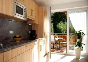 Una cocina con microondas y un balcón con mesa. en Reiterhof Siglgut, en Tarres