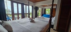 a bedroom with two beds and a balcony with windows at Hotel Manuel Antonio Inn in Quepos