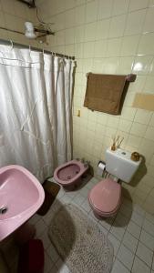a bathroom with a pink toilet and a sink at Casa Zorzal in Paso de la Patria