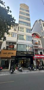 河内Elegant Hotel的一座高大的建筑,前面停有摩托车