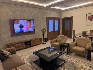 a living room with a tv and a couch and chairs at KumKum Apartments in Pakoto +3 photos