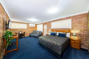 ein Schlafzimmer mit einem Bett und einer Ziegelwand in der Unterkunft Wondai Colonial Motel & Ivory's Restaurant in Wondai