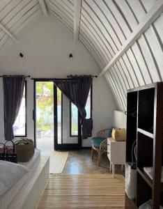 a room with a bed and a living room with windows at TottyHouse Gili Trawangan in Gili Trawangan