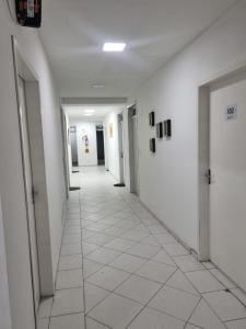 弗洛里亚诺波利斯Hotel FA Andrade的空的走廊,有白色的墙壁和白色的瓷砖地板