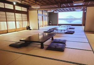 Habitación grande con mesas y una pantalla grande. en 鈴籠城 籠の間 ダブルベッド2台 二段ベッド1台, en Nagahama