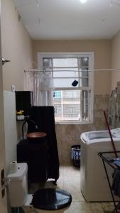 a bathroom with a toilet and a sink and a window at Quarto compartilhado para Homens in Sao Paulo