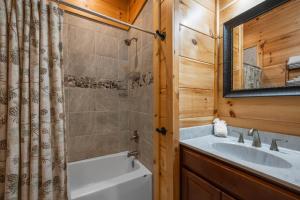 a bathroom with a tub and a sink and a mirror at Hibearnator in Sevierville +8 photos