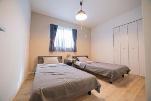 a room with two beds and a window at 無料レンタカー付 ReHaQ宮古島バケーションレンタルハウス in Miyako Island