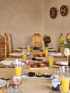 una mesa larga con platos y vasos de jugo de naranja en Urti Villa, en Nzala