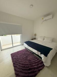 ein Schlafzimmer mit einem großen Bett mit einem lila Teppich in der Unterkunft La casa blanca in Mezcales