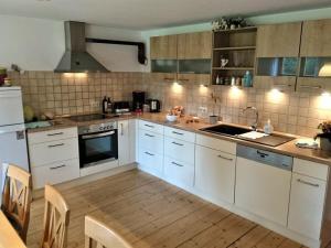 una cucina con mobili bianchi e pavimento in legno di Holiday home with 2 bedrooms a Buchenberg Altre 23 foto