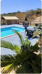 een zwembad met een tafel en stoelen ernaast bij chale bella serra in Jaboticatubas
