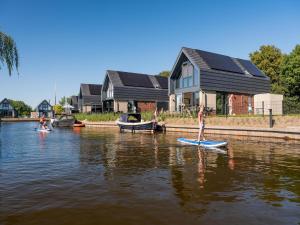 a person is standing on a paddle board in the water at Luxurious detached water villa with jetty in Balk