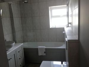 a bathroom with a tub and a sink and a window at Hewlett Apartments in Cheltenham