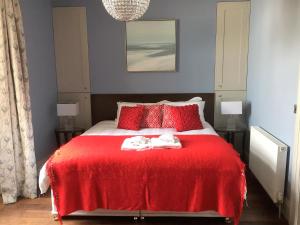 a bedroom with a red bed with two towels on it at Hewlett Apartments in Cheltenham