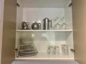 a cupboard filled with dishes and glass jars at Kiwi Cove in Tauranga