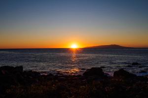 a sunset over the ocean with a mountain in the background at ふとの情景 Futo Nostalgia in Ito