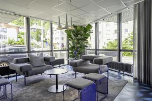 a waiting room with chairs and tables and windows at Prize by Radisson, Solheimsviken Bergen in Bergen