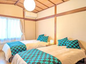 una camera con 2 letti con cuscini blu e verdi di ann近島 無料駐車場2台 階段なし安心の平屋貸切 ファミリーやグループ旅行に最適 a Gifu