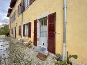 a yellow building with brown shutters and a door at Charmant T2 Larressore - Parking Privé - WiFi Inclus - FR-1-495-156 in Larressore