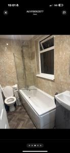 a bathroom with a tub and a toilet and a sink at Cosy Double room in house available with shared bathroom in Hurlet