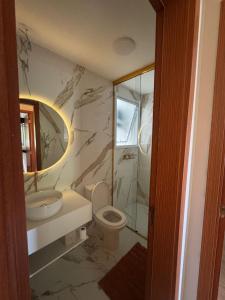 une salle de bain avec un lavabo, des toilettes et un miroir dans l'établissement Apartamentos das Toninhas, à Ubatuba