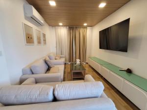 un soggiorno con mobili bianchi e TV a schermo piatto di The wide pool villa trat a Ban Nong Wiwat